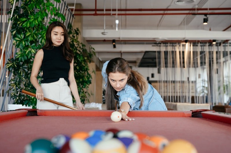 Two ladies playing pool.