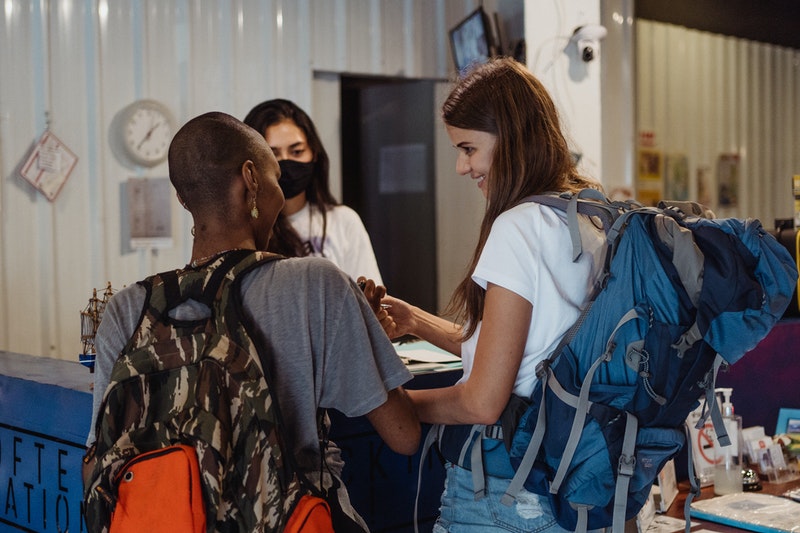 Two young ladies with luggage checking into a hostel