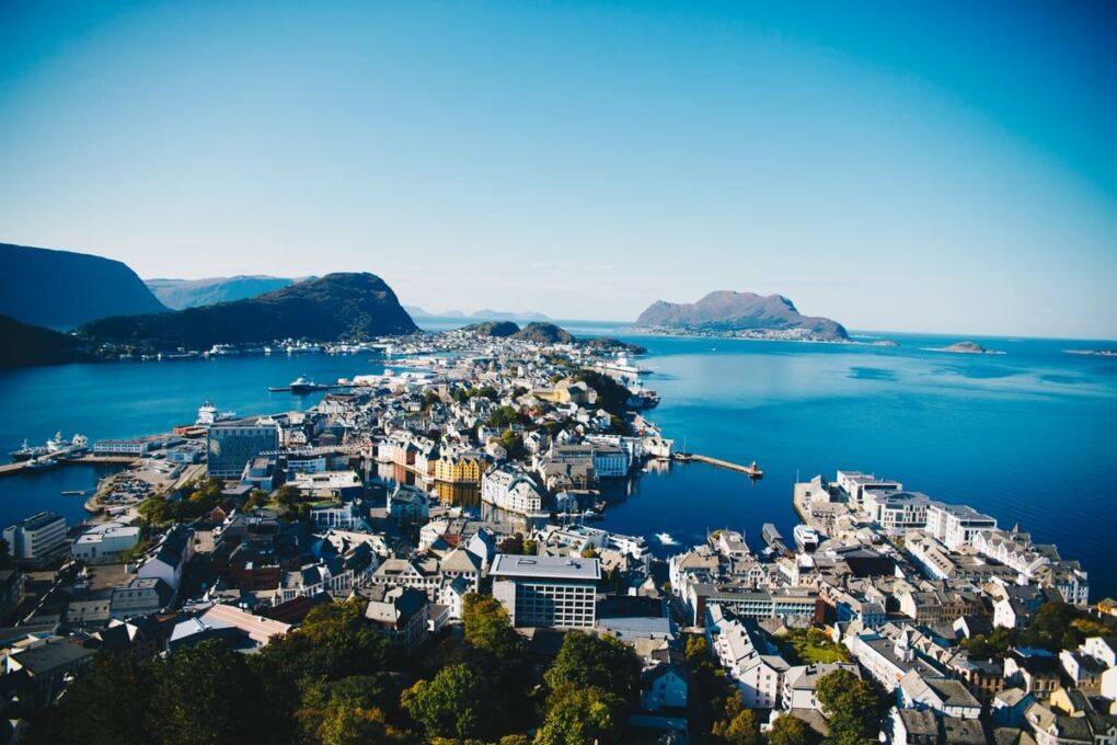 Aerial shot of Alesund City, Norway between a body of water and mountains in the background