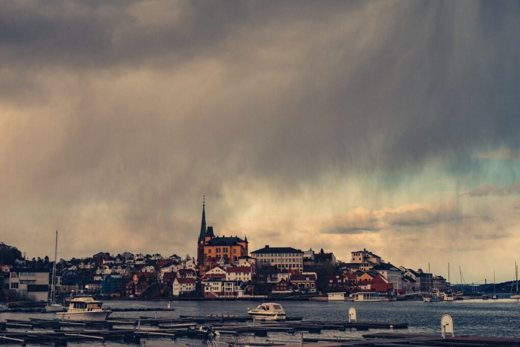 Boats in a harbor with buildings in the background in Arendal City, Norway