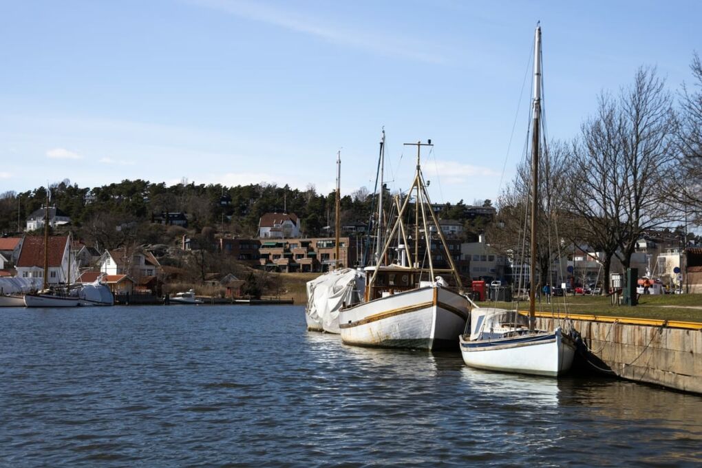 Boats in Glomma River with buildings on a hill behind it in Fredrikstad City, Norway