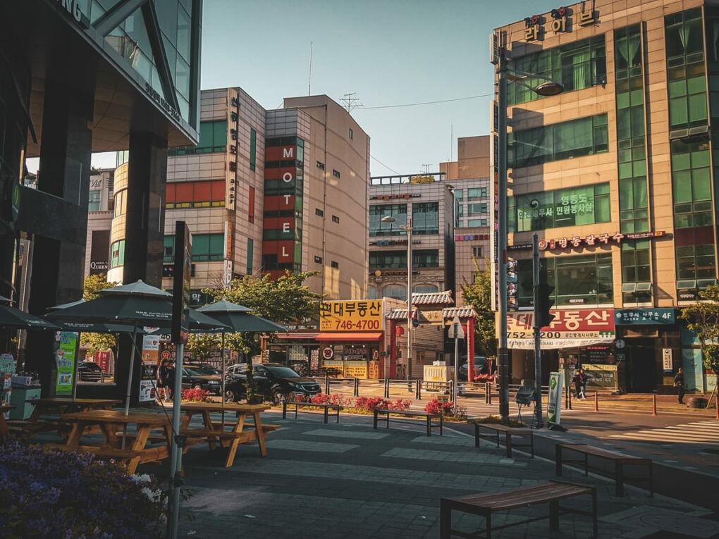 Wooden tables outside a café and a road in Incheon city with buildings surrounding it
