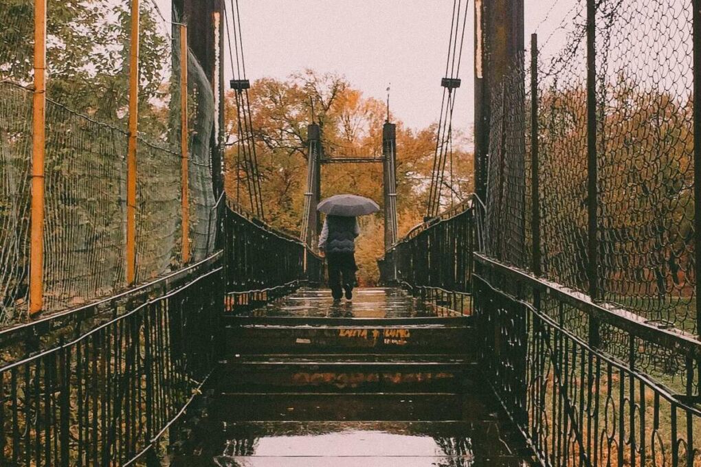 Person walking in the rain on a bridge in Taraz