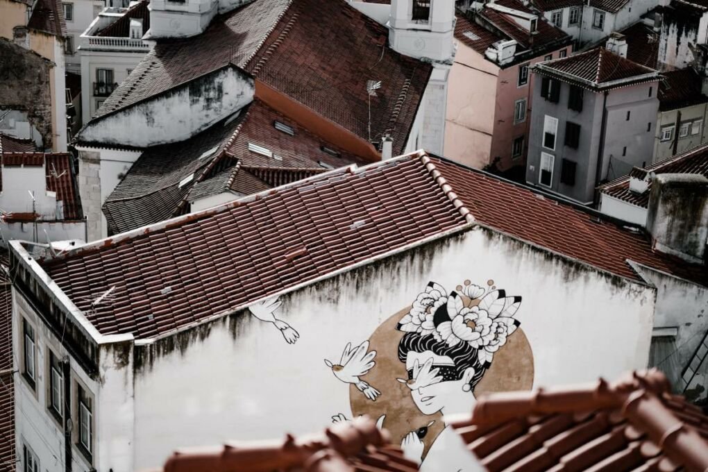 Street art of a lady and birds on the wall of a house 