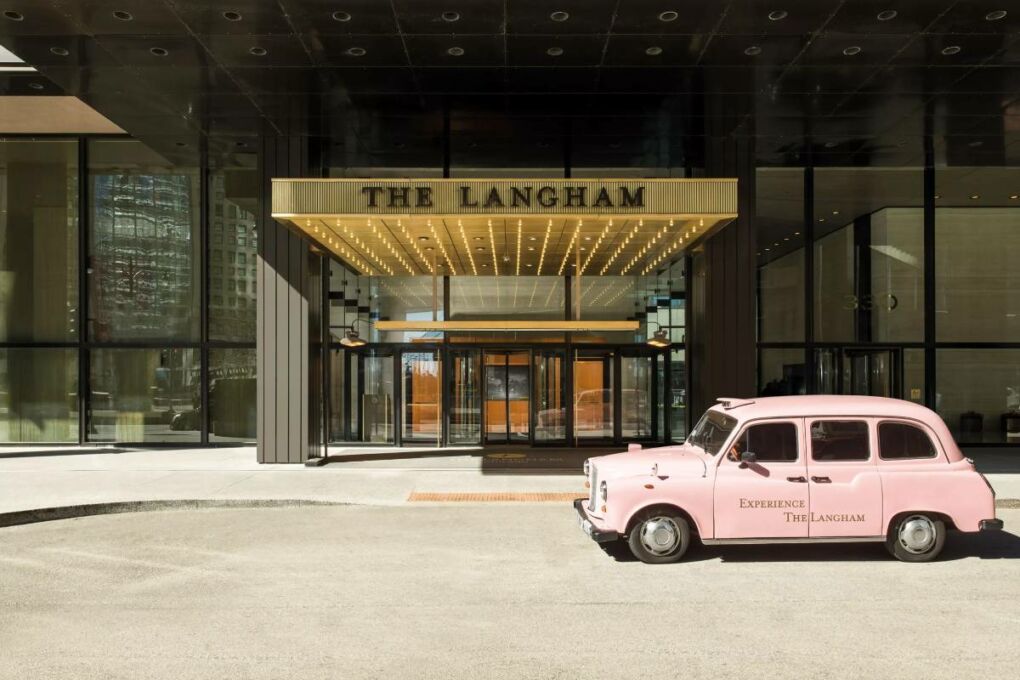 The entrance to the Langham hotel, with a pink British styled taxi to the right of the entrance.