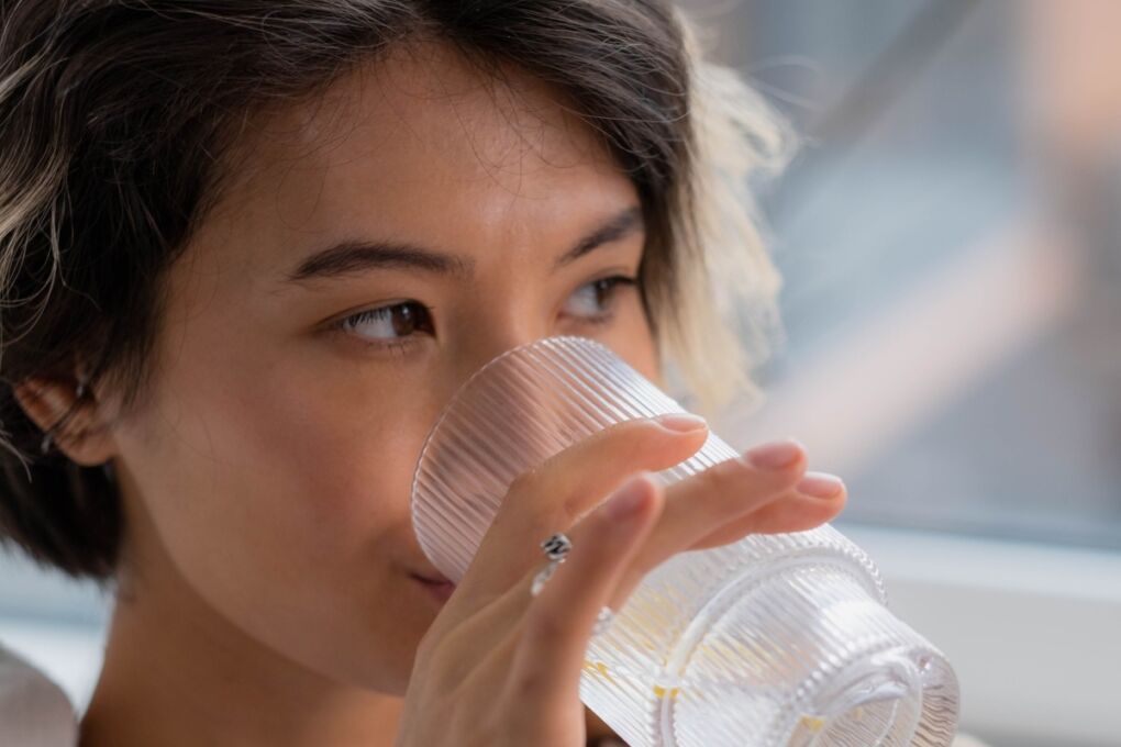 Closeup of a person drinking a clear glass of water