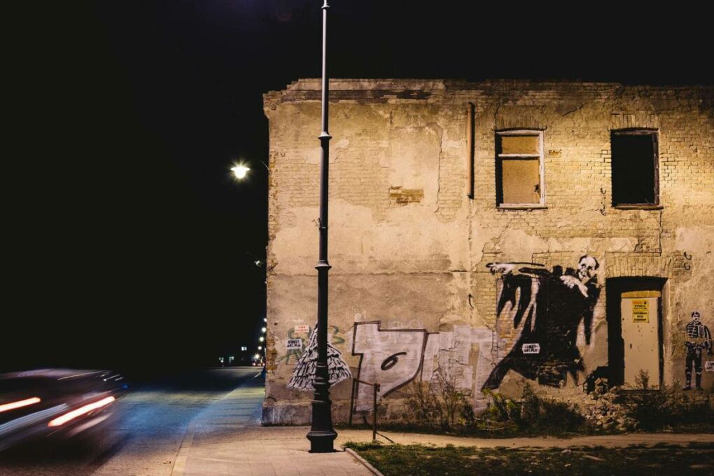 Abandoned building on a dark street with graffiti on it.