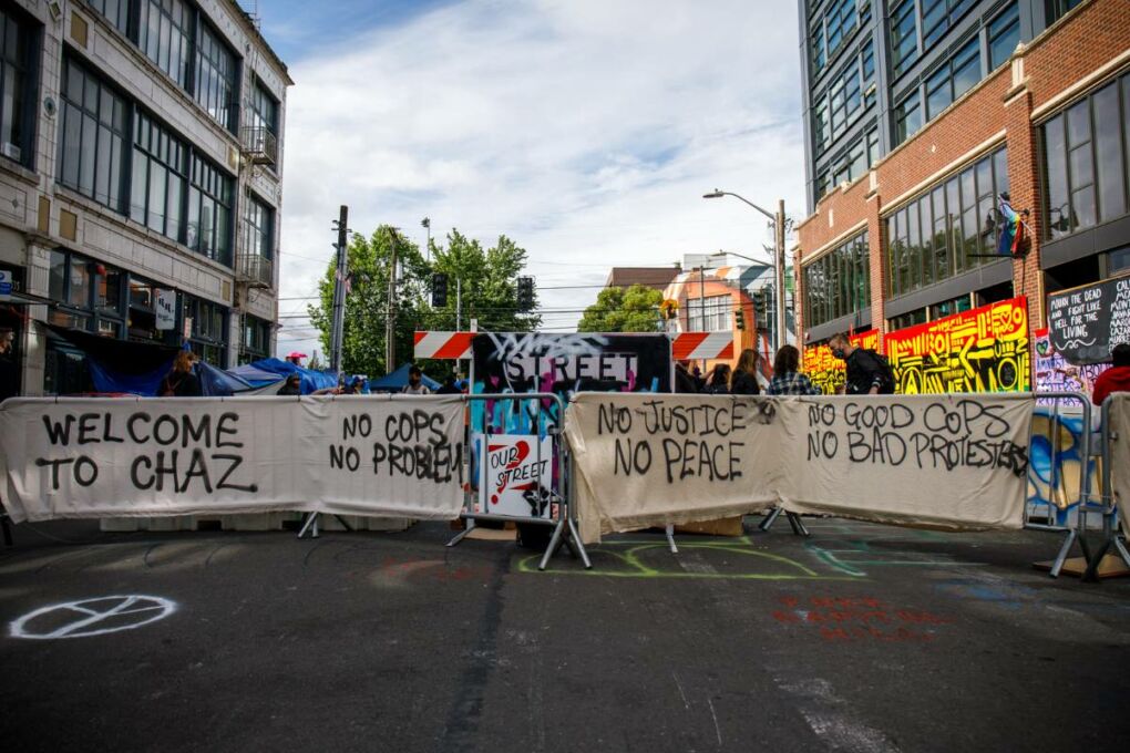 Capitol Hill Occupied Protest road block with spray painted signs that read, "Welcome to CHAZ." "No Cops. no Problem." "No justice. No peace." "No good cops. No bad protestors."