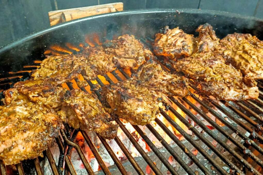 Jerk chicken being cooked on a grill.
