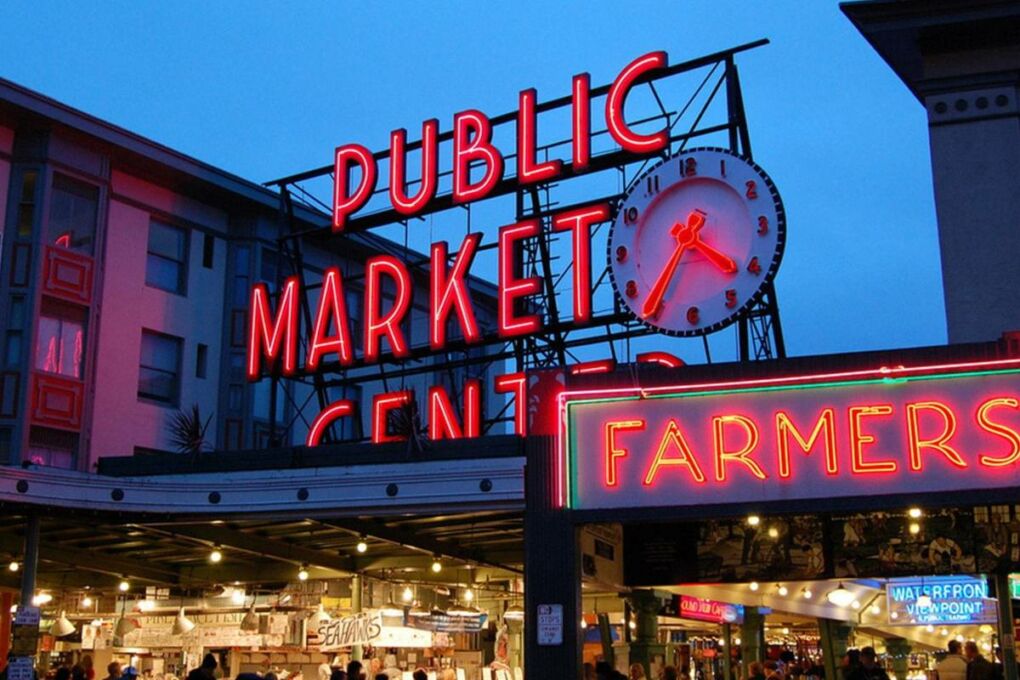 A red neon sign outside of Pikes Place Market that reads "public market center."
