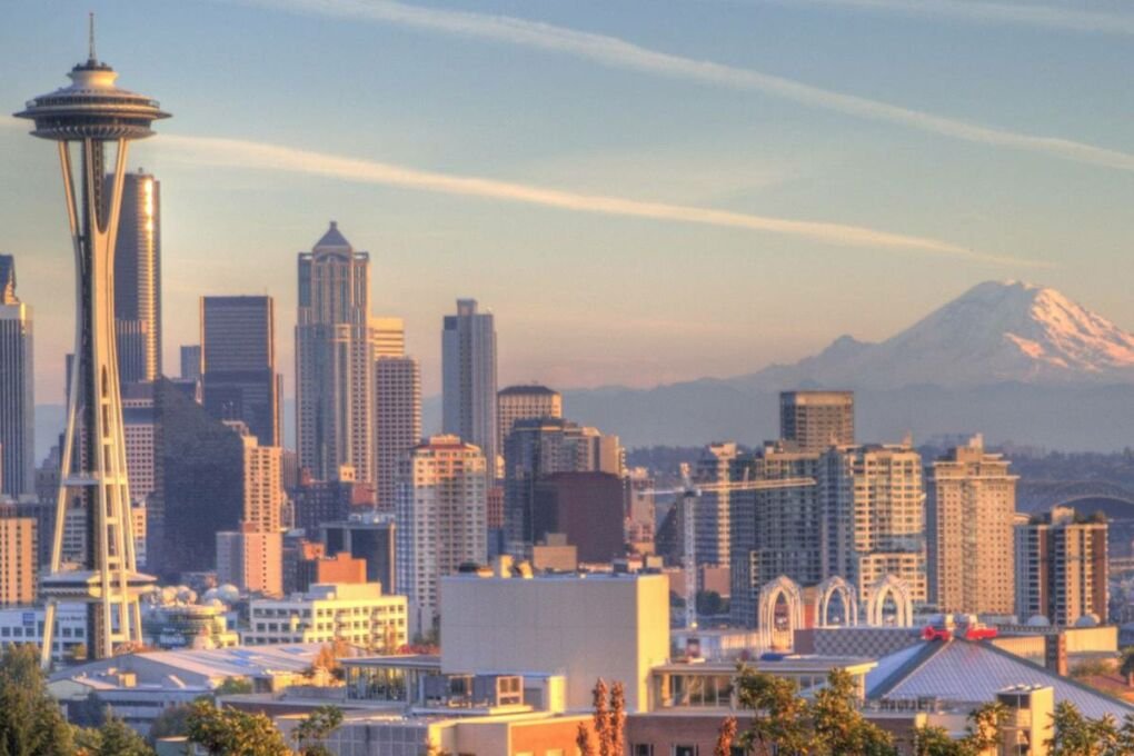 The Seattle city skyline at sunset with a mountain in the background.