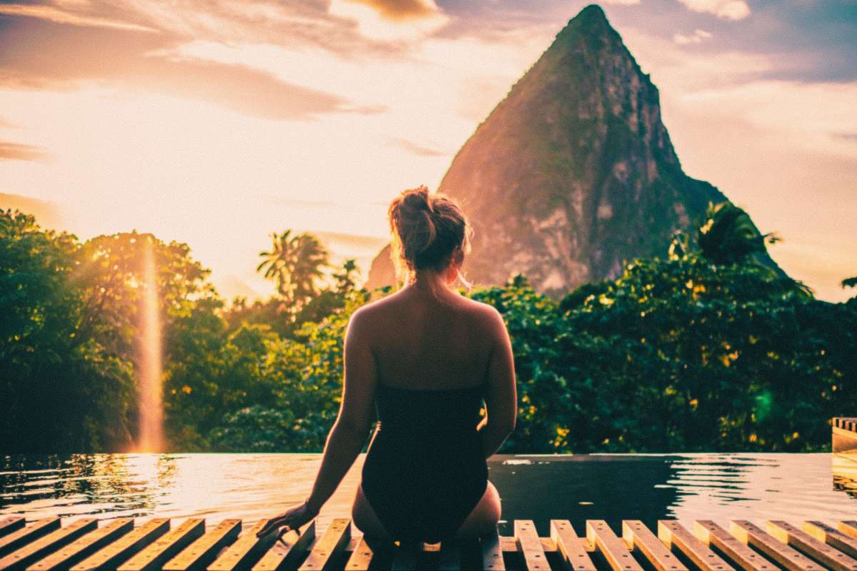 Woman sitting in front of Gros Piton and Petit Piton Peaks at sunset.