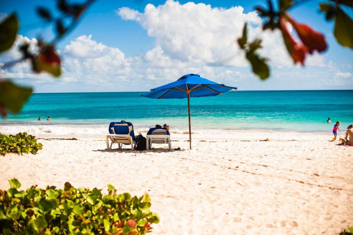 Two people relaxing on sunloungers on the beach