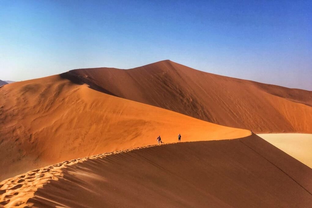 Tourists walking across Sossusvlei dunes in Namibia