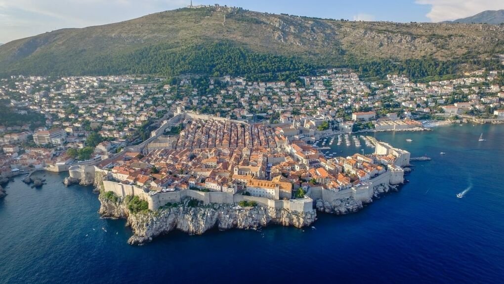 aerial shot of bay port city of Dubrovnik|boats in port|city on coast|city overlooking water|city in forest by sea|art pavilion in overcast setting|church and square|cathedral entrance siberia|city looming over a waterwaay in croatia|roman amphitheater in pula|small harbour in Hvar croatia