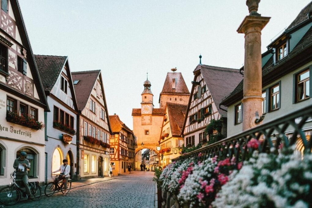 white and pink petaled flowers on metal fence near concrete houses|Image of neuschwanstein castle in Germany|Image of a group of people walking outside a building in Bremen|Image of Berlin in lights|Image of Panorama of Marienplatz in Munich|image of lake houses and landscape in Cochem, Germany|Image of beggar in Germany|image of the Marienplatz night lights|Image of a large crows of people in Berlin|aerial view of city buildings during sunset