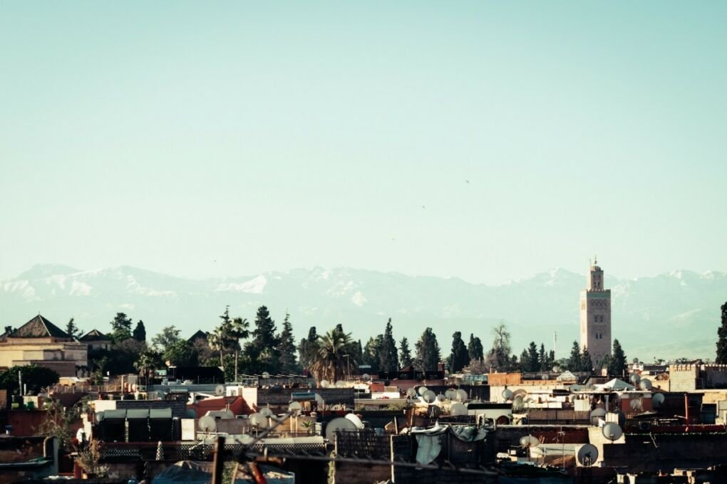 View of Marrakech and the Atlas Mountains|The Bahia Palace tourist attraction|A busy Medina souk market|A camels in the Sahara Desert|A view of the houses in Marrakech||A safe luxury hotel in Marrakech|A view of the houses in Marrakech|A colorful souk market|A quiet winding street in Marrakech