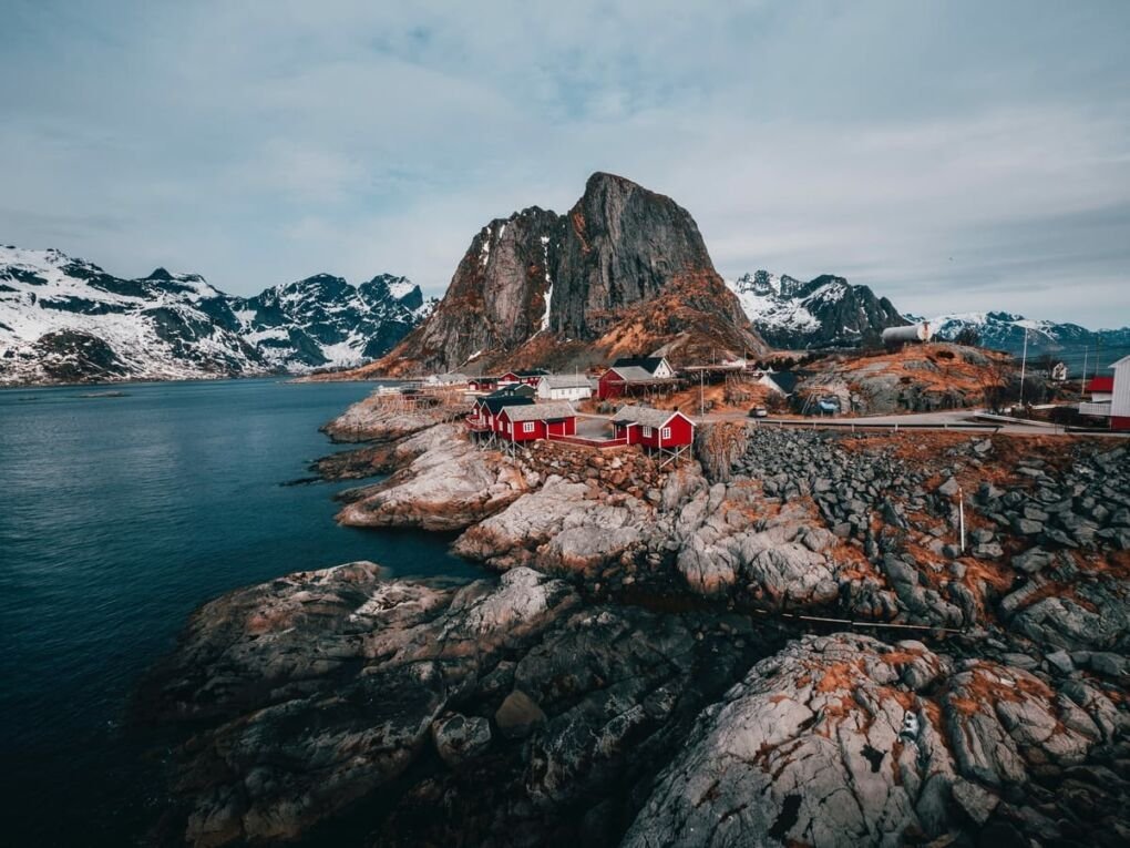 Aerial view of rock formation, body of water and houses on Lofoten islands in Norway||||||||||