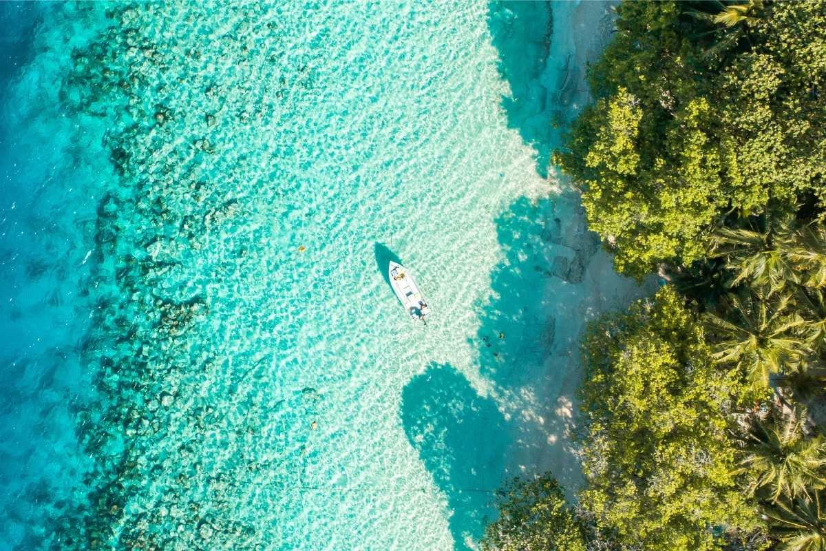 A boat sailing near the shore in The Maldives|Aerial view of Male The Maldives|aerial view of the Maldives islands|Boat sailing in Hulhumale in The Maldives|Sea and land of Dhigurah Maldives|View of Fuvahmulah's coastline|A colorful house in Maafushi The Maldives|Maldivian locals in traditional dress|Palm trees in Dhidhdhoo|View of a lush Maldivian island and underwater reef|Aerial view of Thulusdhoo Island in The Maldives