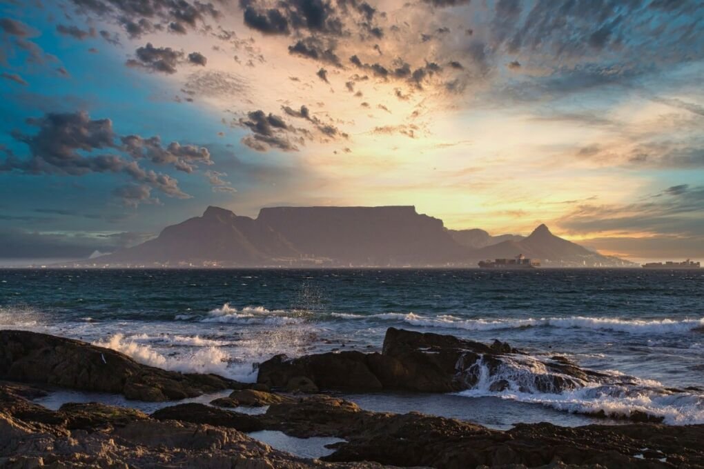 beach view of table mountain during sunset|boulders bay penguin beach|table bay harbour at night time|camps bay|groot constantia vineyard building|bay hotel v&a waterfront|bo-kaap street colourful buildings|cape town city center building|colourful huts on beach|cape town architecture at night by the sea