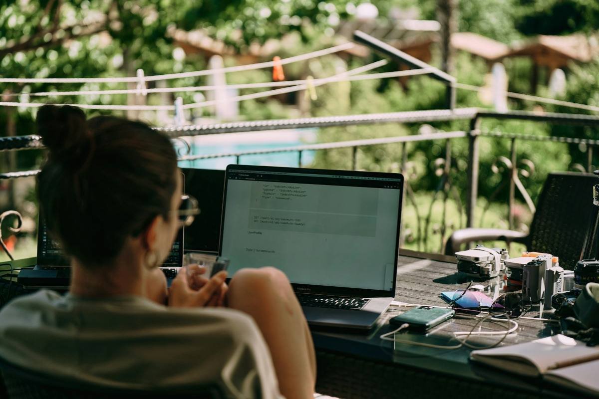 A person working remotely outside with a laptop on a table